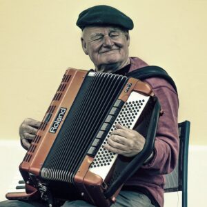 Homme âgé, souriant et yeux fermés, jouant de l'accordéon